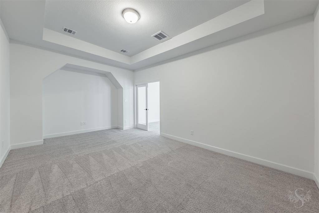 Tucked behind the double doors, the media room offers a quiet, enclosed space ideal for movie nights or watching sports events. Its cozy layout and architectural niche make it easy to imagine your dream theater setup.
