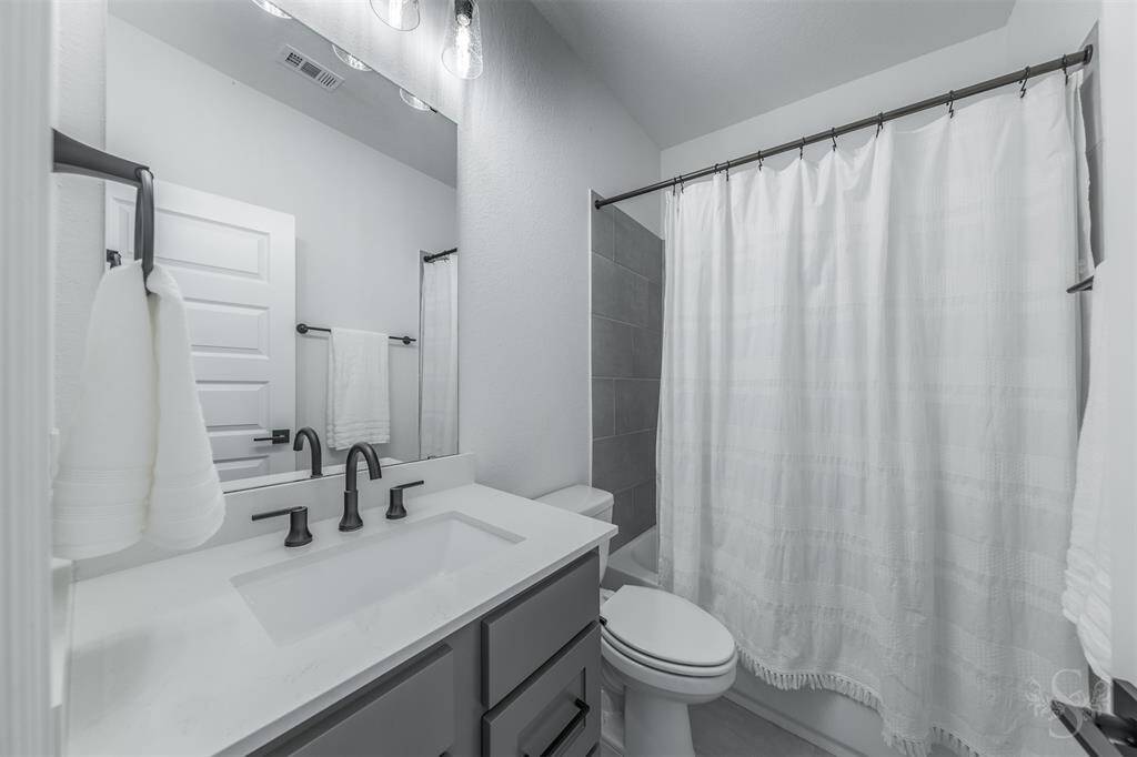 A secondary upstairs full bath offers a sleek modern design with quartz counters and matte black fixtures. The tub/shower combo and ample vanity space make it both functional and elegant.