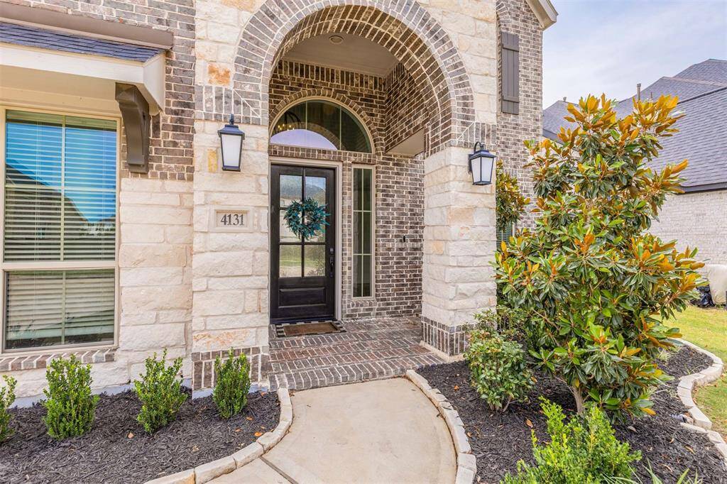 The sophisticated brick and stone exterior creates a timeless façade that immediately elevates the home’s presence. A gracefully arched entryway and detailed architectural accents offer a warm welcome and set the tone for the elegance found inside.