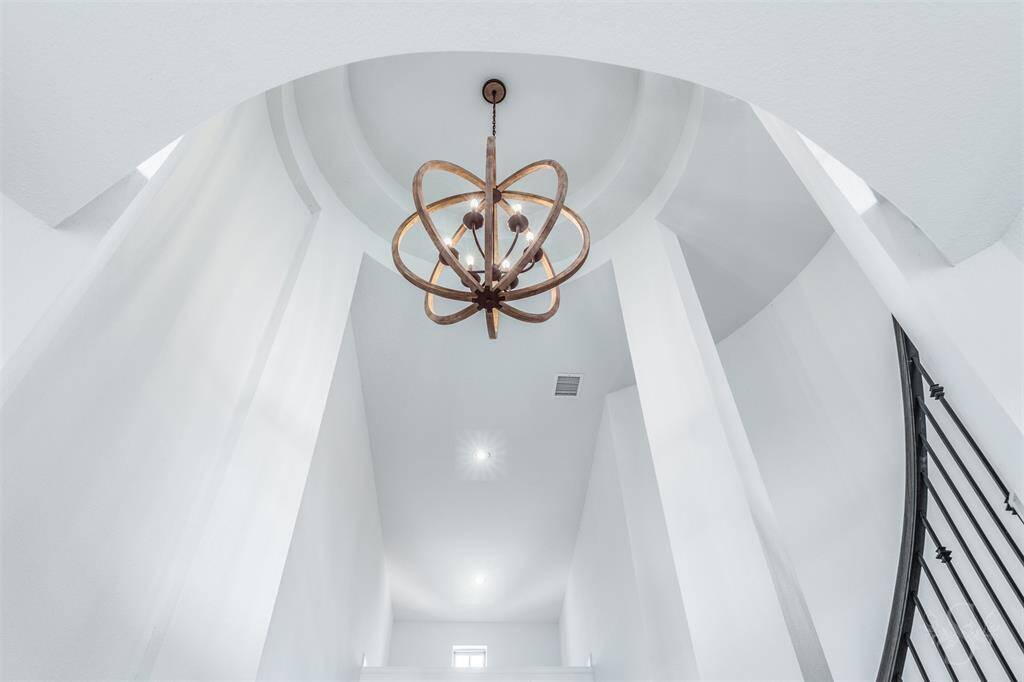 A dramatic rotunda ceiling frames the show-stopping chandelier, casting a warm glow over the stunning entry below. This architectural focal point sets the tone for the home’s elevated style.