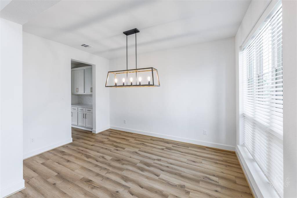 Entertain with ease in the formal dining room, highlighted by an eye-catching linear chandelier and expansive front-facing windows. Seamlessly connected to the butler’s pantry and kitchen, this space blends sophistication with functionality.