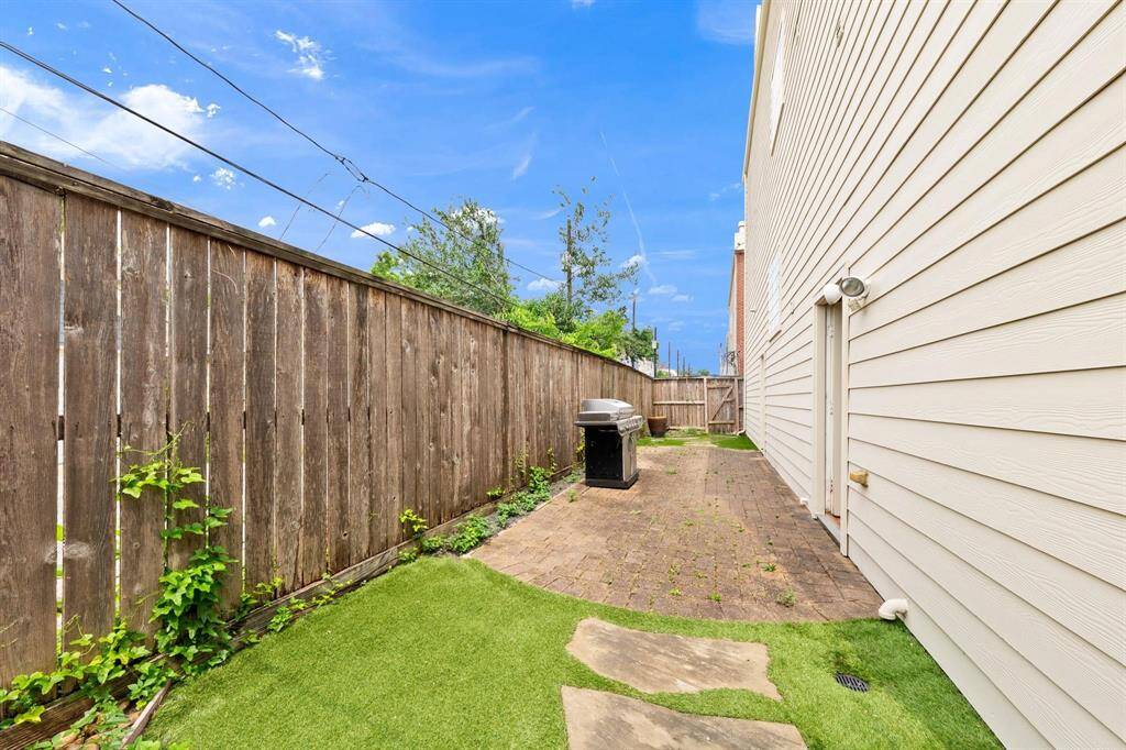 Private backyard with attractive brick paver patio, offering ample space for a grill and outdoor seating