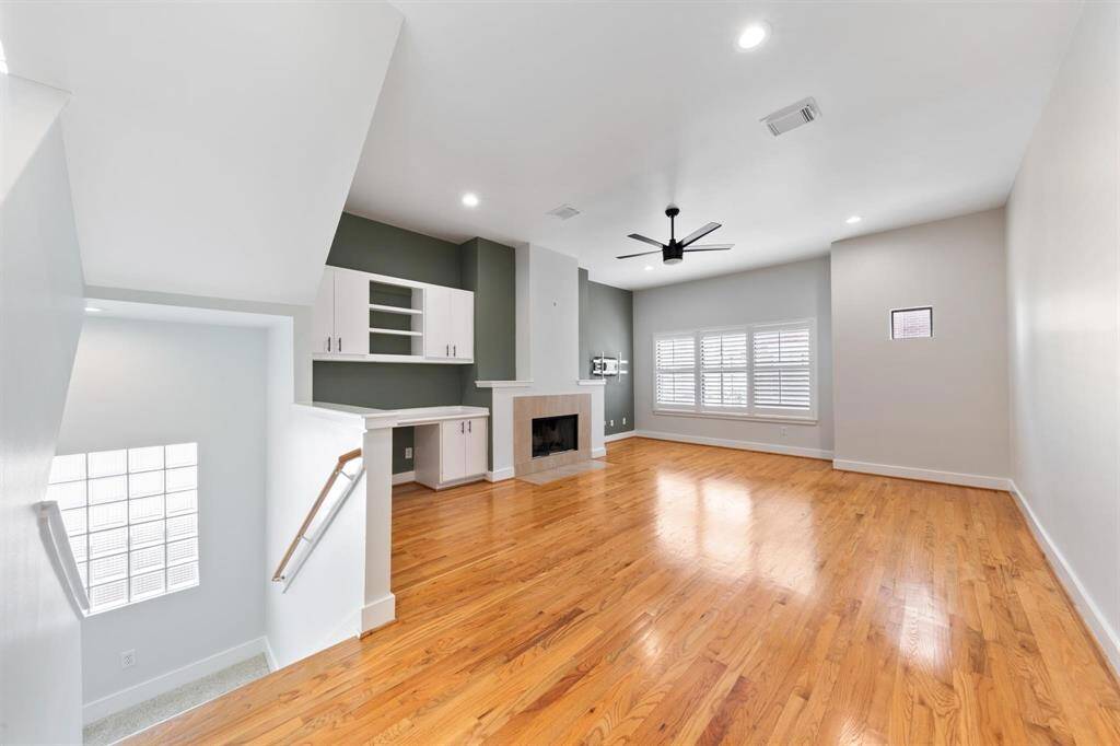 Second-floor living space with high ceilings, recessed lighting, and a gas log fireplace—offering a bright, inviting atmosphere with plenty of room to relax or entertain.