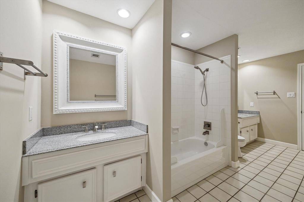 Indulge in this elegant bathroom featuring a sleek vanity, modern lighting, and a spacious shower-tub combo. Perfect for relaxation and style.