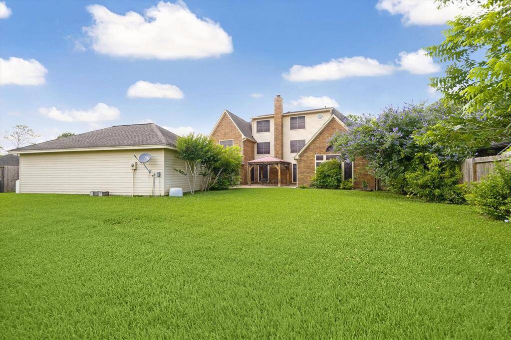 Expansive backyard with serene green space behind.