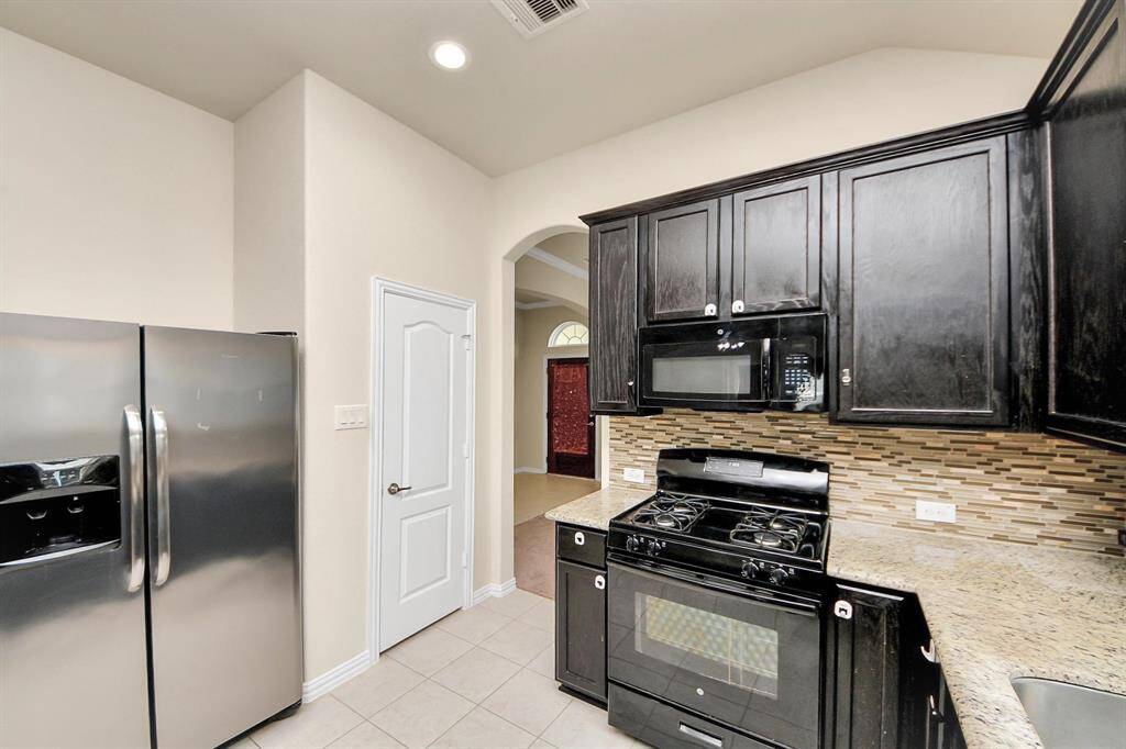The space features a gas stove, built-in microwave, and granite countertops. An arched doorway leads to another room, enhancing the open feel.