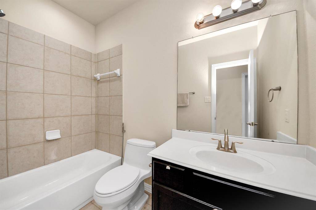 This bathroom features a clean, modern design with a tiled shower and bathtub, a sleek white vanity with a mirror above, and bright lighting.