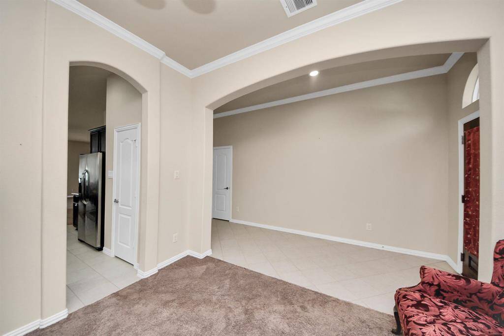 Welcoming entryway with tile flooring leading to a spacious living area. Features an arched doorway to the kitchen and a cozy carpeted section. Neutral colors enhance the open feel.