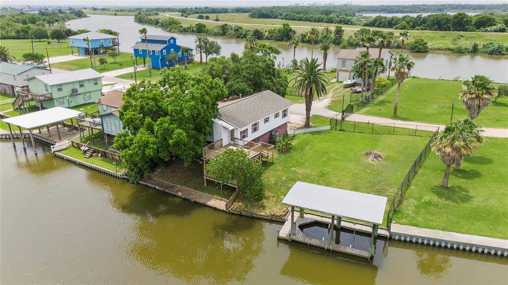 Aerial view of the property showcasing the spacious lot, private dock with boat lift, dual-level deck, and lush surroundings—ideal for fishing, boating, and entertaining.