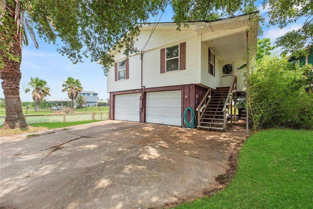 Charming raised home with a welcoming staircase and wraparound trees providing natural privacy and shade.