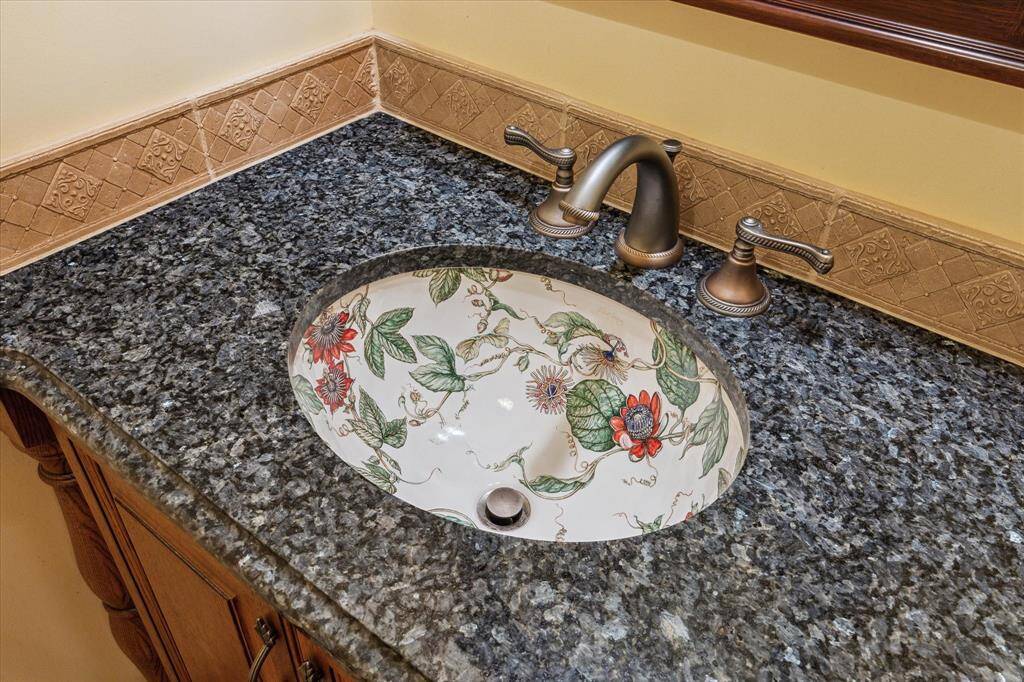 GORGEOUS CUSTOM SINK IN POWDER ROOM IS SURROUNDED BY GRANITE AND STUNNING DECORATIVE TILE BORDER