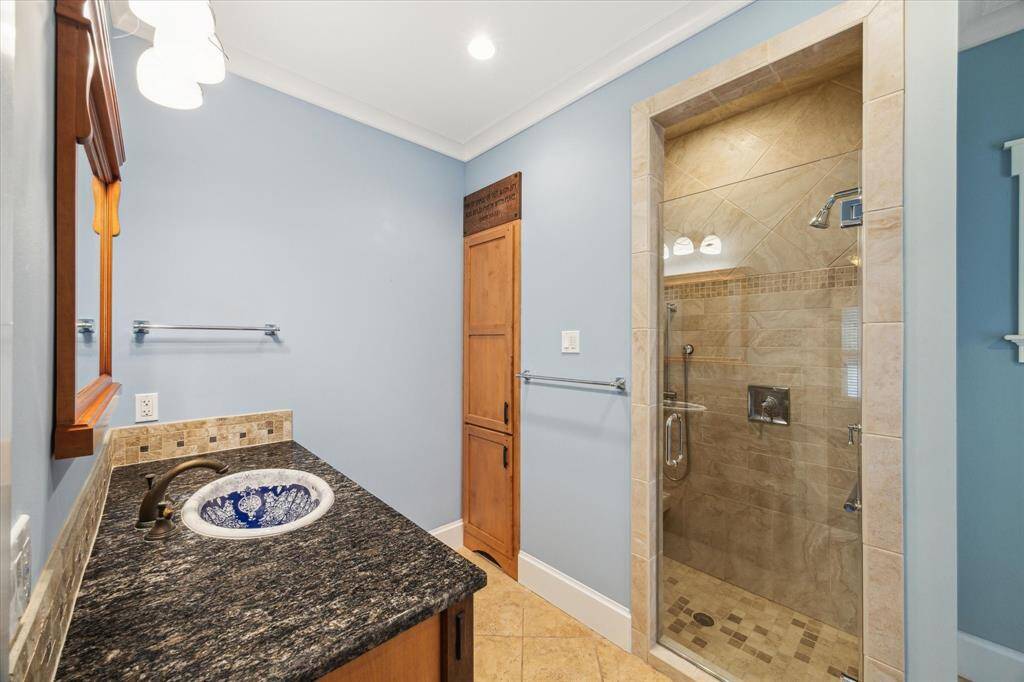 PRIMARY BATH OFFERS A GRANITE VANITY AREA SURROUNDING THE CUSTOM SINK. SEAMLESS SHOWER OFFERS CUSTOM CERAMIC TILE