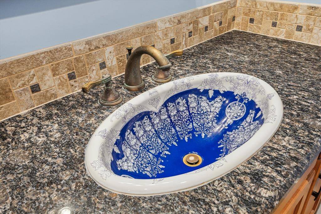 CUSTOM SINK IS S TRUE FOCAL POINT, LUXURIOUS GRANITE COUNTER TOPS FRAMED WITH A TILE BORDER AND BRASS FIXTURE