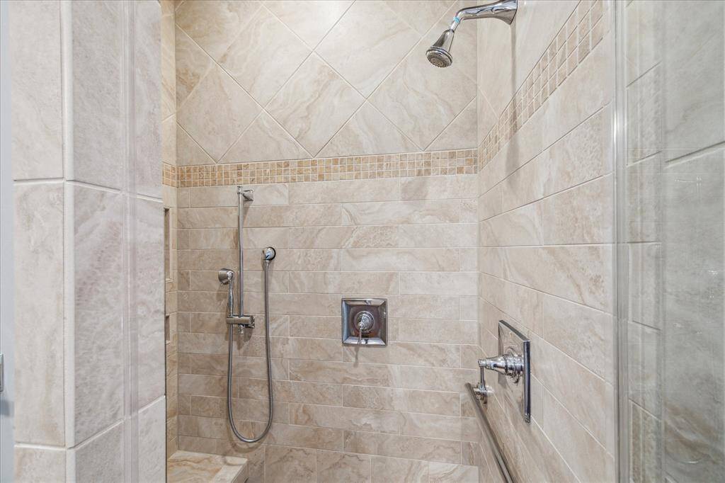RELAX FROM A LONG DAY IN THIS SEAMLESS SHOWER OFFERING SEATING AND DUAL SHOWER HEADS, AND CUSTOM TILE