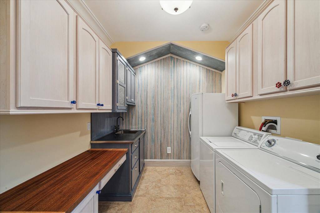 A WALL OF CUSTOM BEADBOARD LINES THE BACK WALL ADDING TEXTURE TO THIS SPACIOUS UTILITY ROOM. INCLUDED ARE THE FREEZER, WASHER, DRYER. CUSTOM CABINETS FEATURE THIS FUN HARDWARE, A BUILT-IN SINK AND GORGEOUS ONE-OF-A KIND FOLDING TABLE