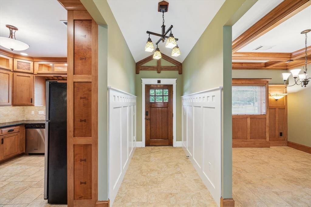 THIS STUNNING FRONT DOOR, CUSTOM STAINED IN RICH WALNUT, MAKES AN UNFORGETTABLE FIRST IMPRESSION. IT'S BEAUTIFULLY ACCENTED WITH ELEGANT LEADED GLASS PANELS AND FRAMED BESPOKE MOLDING THAT ENHANCES ITS ARCHITECTURAL CHARACTER. THE EXQUISITE CHANDELIER CASTS LIGHT OVER THE PERFECTLY ETCHED PANELED WALLS. A HANDCRAFTED WOOD DETAIL ABOVE THE DOOR ADDS SOPHISTICATION TO THIS ENTRYWAY