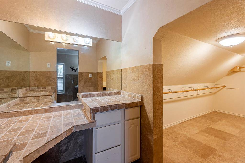 Large custom closet with built-in storage and spacious vanity area with mirror wall.