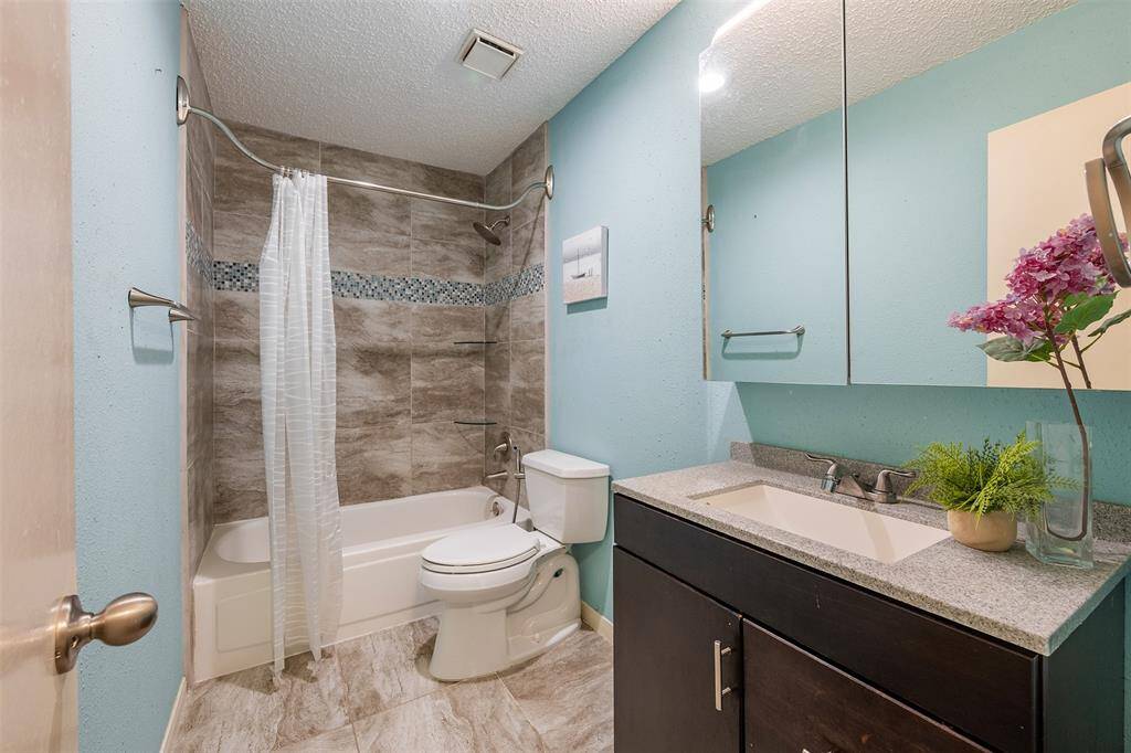 This updated bathroom features clean tilework with mosaic accents and granite vanity.