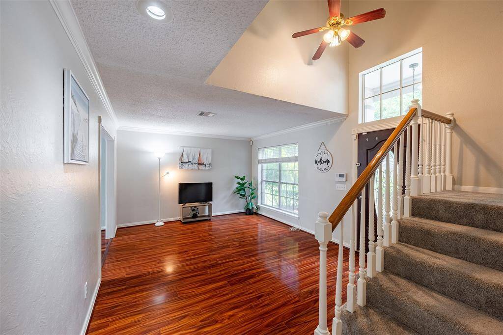 Beautiful formal living room with wood flooring and large windows that fill the space with natural light, seamlessly connecting to the formal dining area.