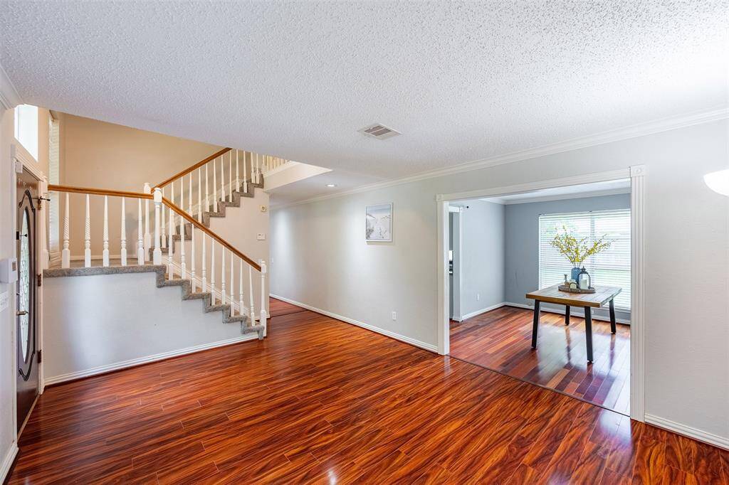 Beautiful formal living room with wood flooring and large windows that fill the space with natural light, seamlessly connecting to the formal dining area.