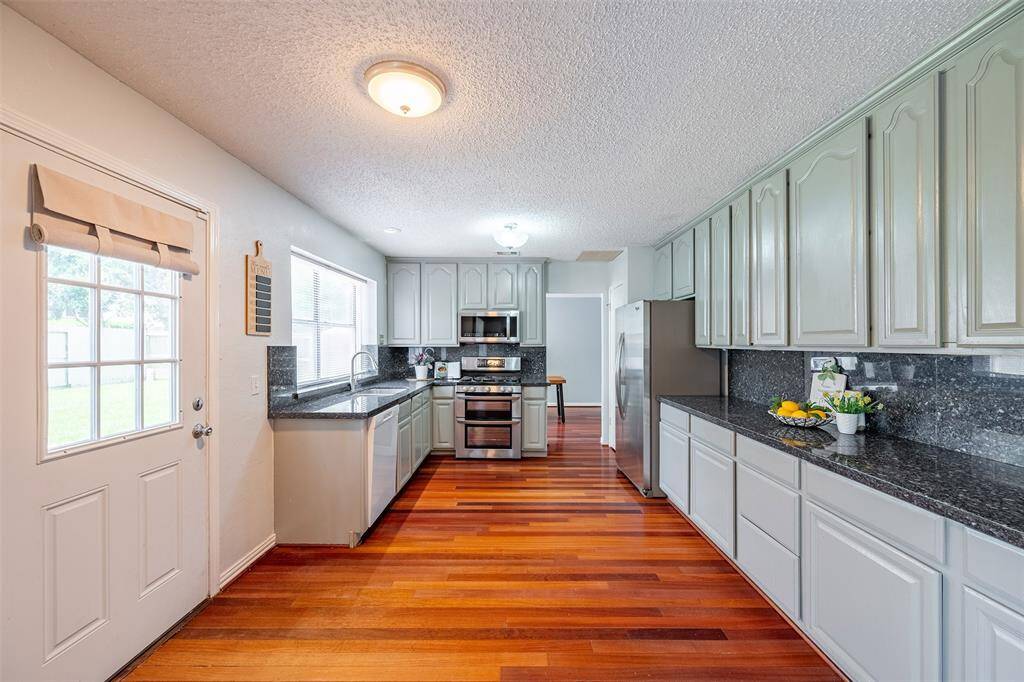 Spacious kitchen boasts granite counters, ample cabinet space, stainless steel appliances, and brand-new (2025) dishwasher and garbage disposal.