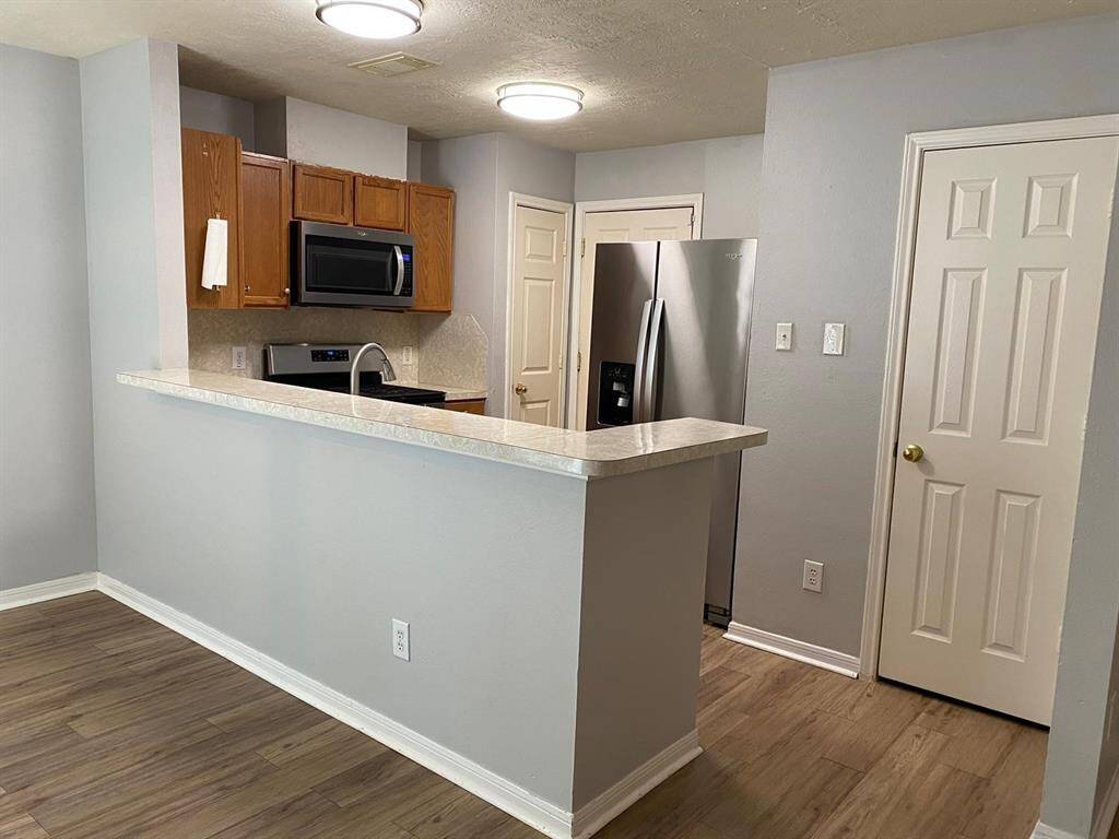 This room features a modern ceiling fan, wood-style flooring, and ample natural light from multiple windows with blinds. The neutral wall color enhances the spacious feel.
