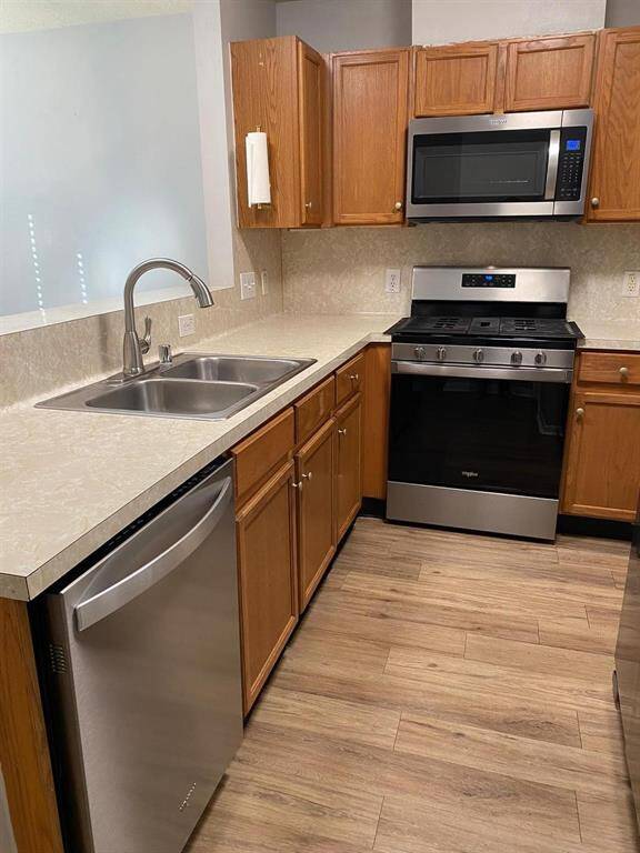 This kitchen features modern stainless steel appliances, including a microwave and gas stove, complemented by warm wooden cabinetry and light countertops.