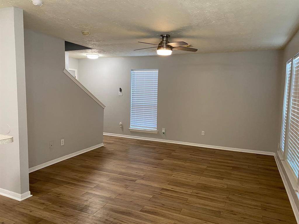Modern kitchen with stainless steel appliances, including a microwave, dishwasher, and gas stove. Features wooden cabinets, a double sink, and spacious countertops. Light wood flooring adds warmth to the space.