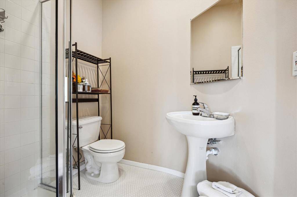 Ensuite bathroom with walk-in shower, pedestal sink and new classic white hex tile flooring- simple clean and thoughtfully updated