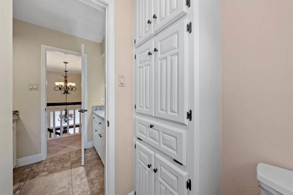 Lots of storage with built-in white storage cabinets, and adjacent to the dressing area with granite countertops on both sides and sinks with lots of vanity space.
