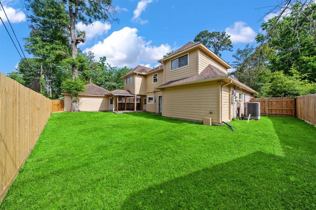 This spacious backyard with lush green grass and a new wooden privacy fence is ready for entertaining. There is also a patio area, perfect for outdoor gatherings.