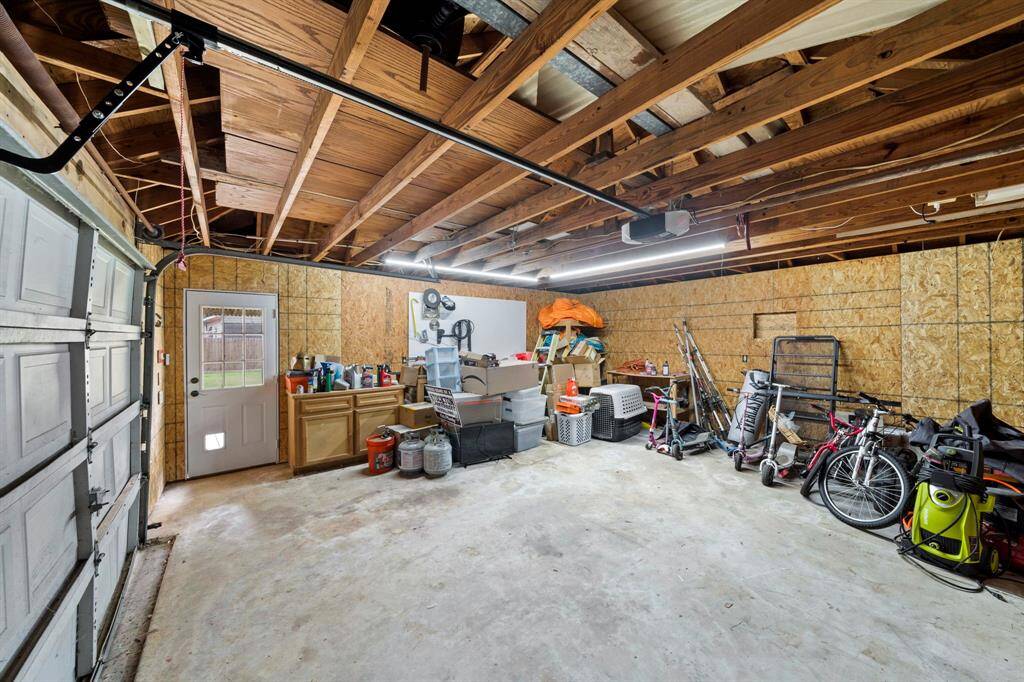 The garage is well insulated with plywood and includes a work area with cabinets with access to the backyard through a side door. Ideal for organizing tools and outdoor equipment. It has extra storage up on the rafters.