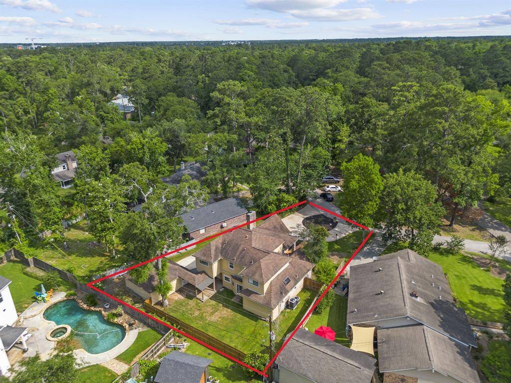 This two-story home has a large backyard, outlined in red for clarity. It's located in a lush, wooded neighborhood, offering privacy and natural beauty. The property is part of a serene residential area in a golf course community.