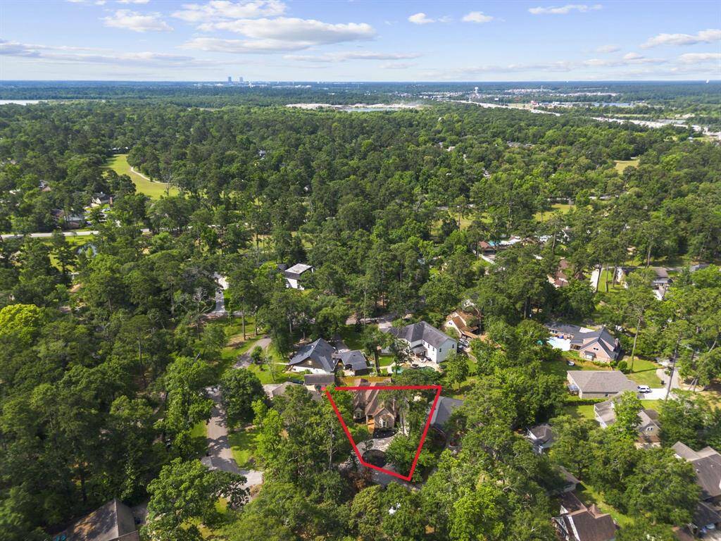 Another aerial photo showcasing the home highlighting its spacious lot and proximity to other well-maintained homes. The area appears serene, with abundant greenery and a distant view of the city skyline.