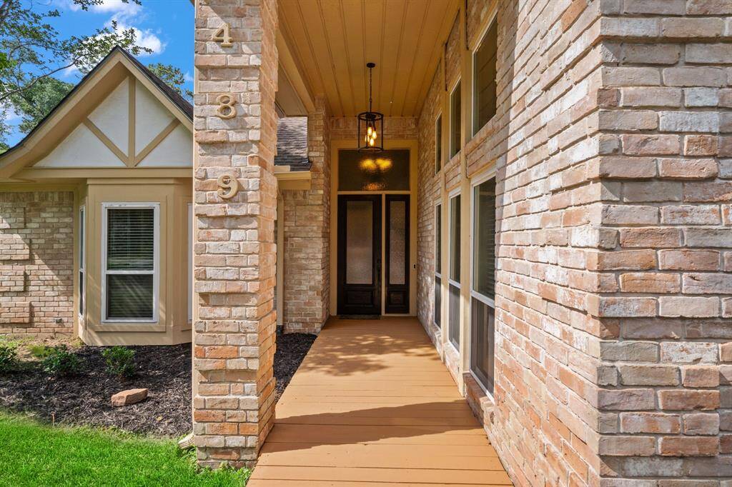 Charming entrance with a brick exterior, elegant front door, and a covered walkway. The house features large double pane windows and well-maintained landscaping, creating a warm and inviting curb appeal.