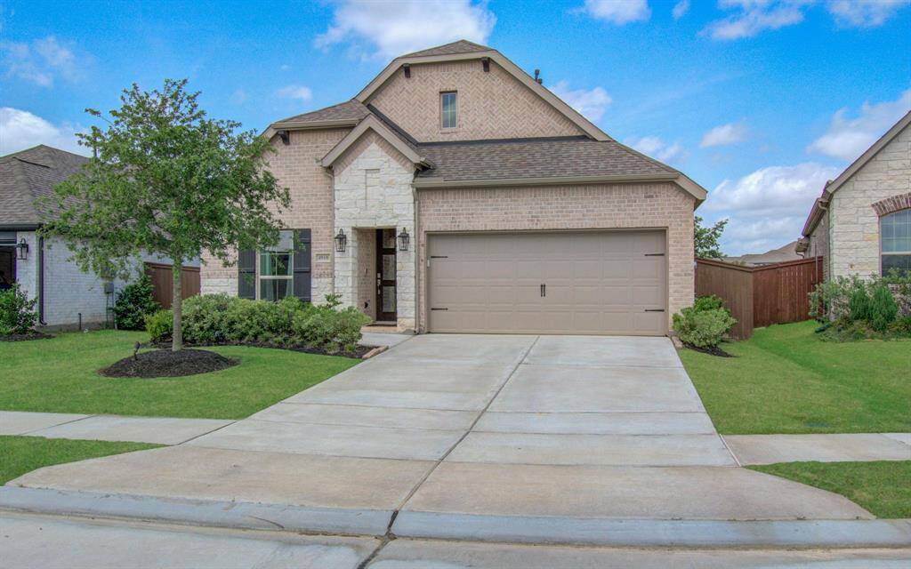 This home boasts high ceilings, a charming brick and stone façade, complemented by a spacious two-car garage and meticulously landscaped front yard.