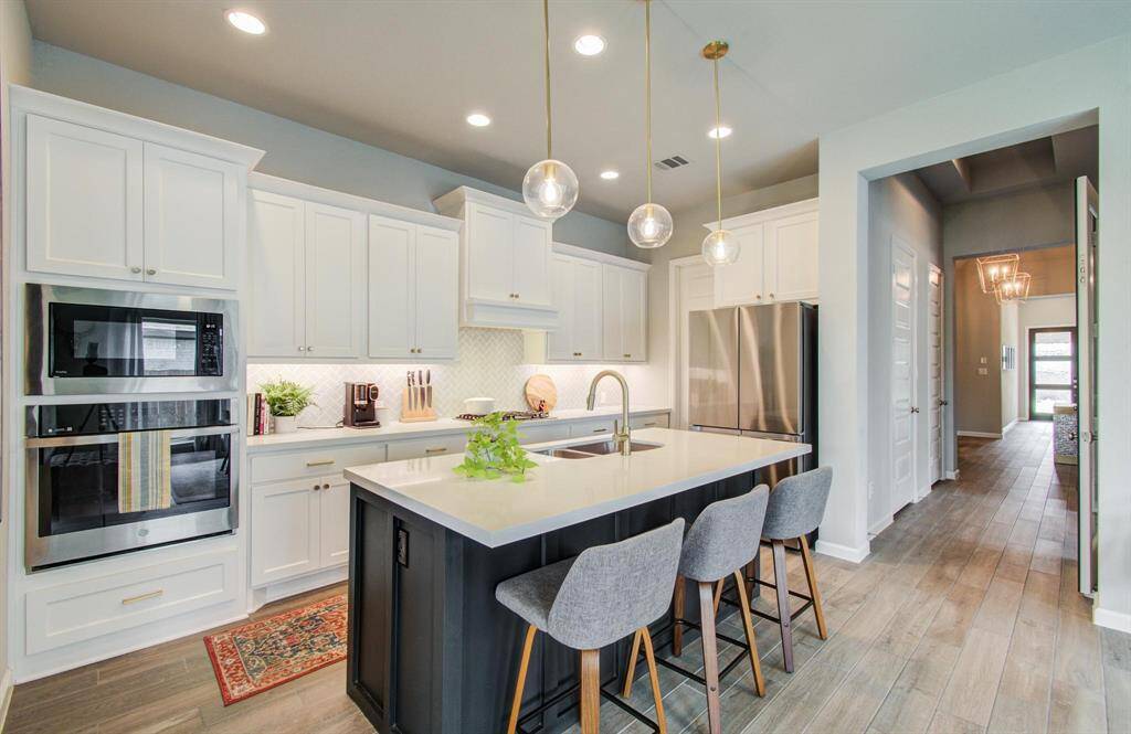 Step into the elegant coffered extended entryway, leading you past a versatile game room to the heart of the home. The open-concept design seamlessly connects the kitchen, dining area, and family room, creating an inviting space for both relaxation and entertainment.