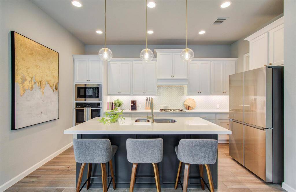 The chef-inspired kitchen is a culinary enthusiast's dream, featuring a generous island with built-in seating, a deep walk-in pantry, and sleek quartz countertops.