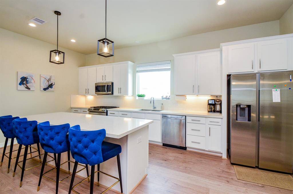 This sparkling urban kitchen rivals any suburban kitchen! Huge 'traveling' space defines a cook's dream 'workshop', with white cabinetry and counter space everywhere you land; a great big window over the sink, shining stainless steel appliances, and a long island, with long quartz countertop for multiple stools below.