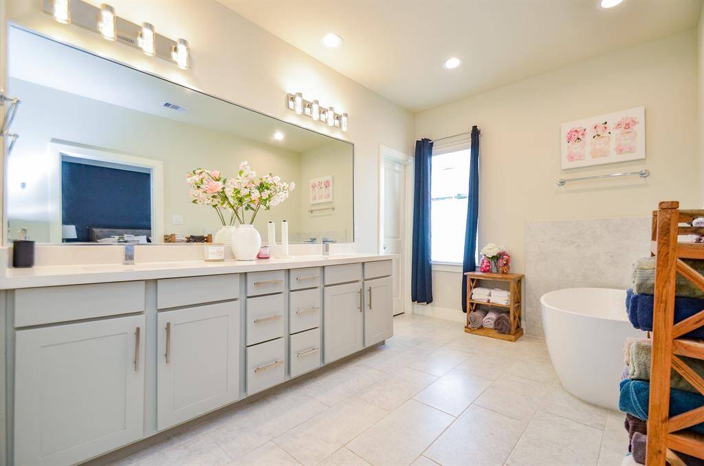This amazing, huge primary ensuite bath will cater to every personal rhythm and creature comfort, with wide open tile floor space; double sinks, above sharp, plenty of contemporary cabinetry, wall-wide mirror, and trim contemporary lighting, above. And . . . just look at the large window!