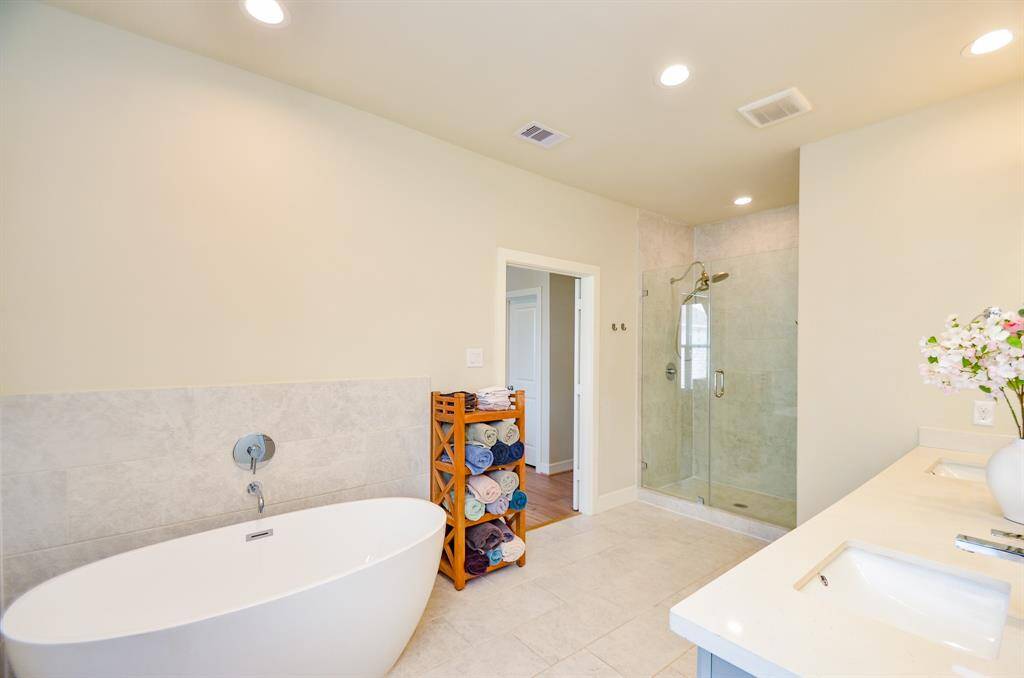 The huge, rimless, glass enclosed shower is nicely placed in a corner alcove.