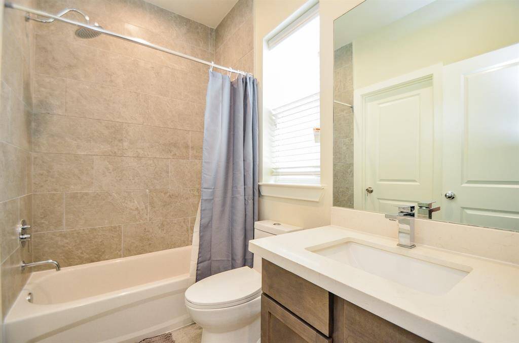 Dreamy earth tones fill an additional full bath on the first floor, which has another welcomed window and combined shower/bathtub.