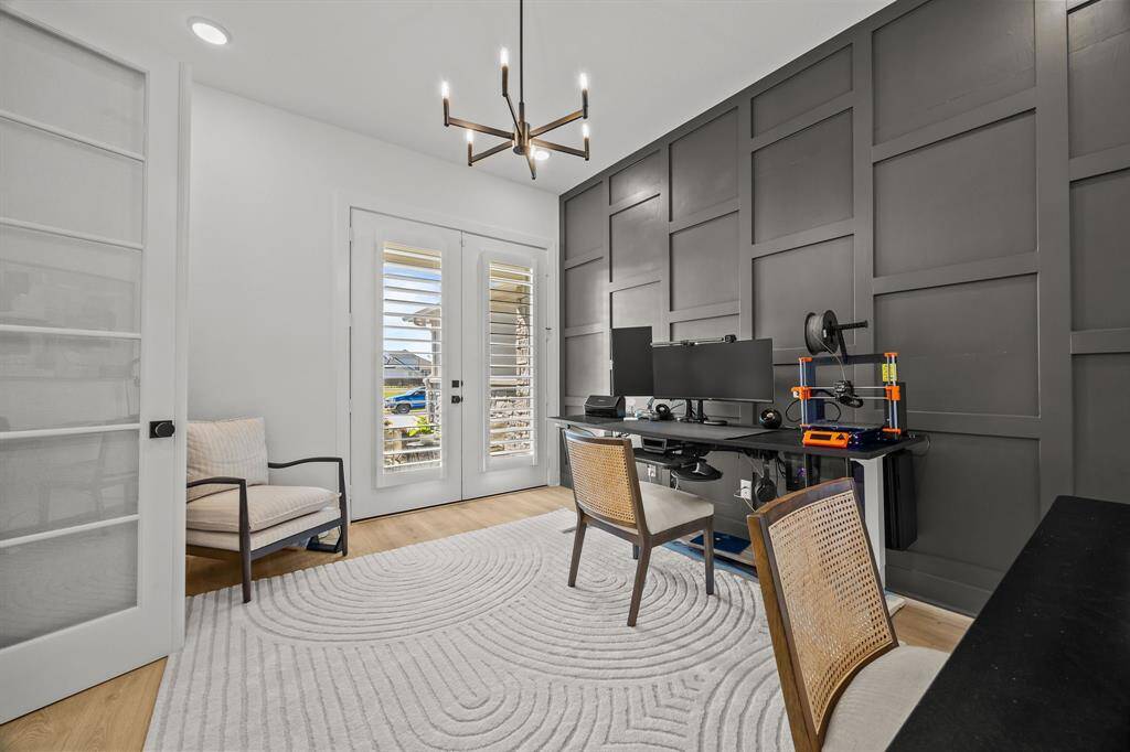 This sophisticated modern study showcases a custom accent wall and French doors leading to a charming front garden alcove.
