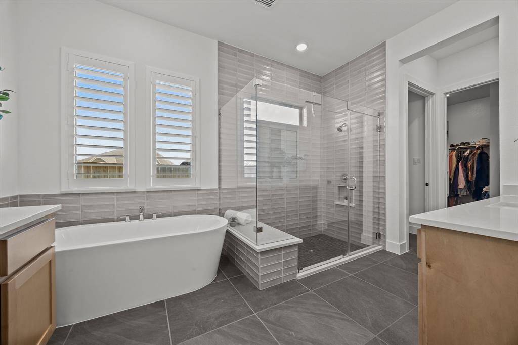 The owner’s retreat bathroom rivals a luxury spa, designed with individual space in mind, featuring separate vanities, a massive sleek shower, and a relaxing soaking tub.