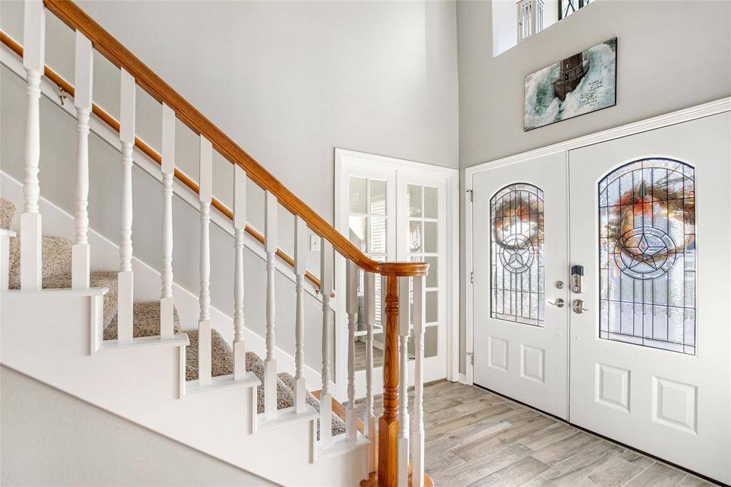 Step into your home with this grand entryway, featuring a stunning staircase and beautiful stained glass doors.