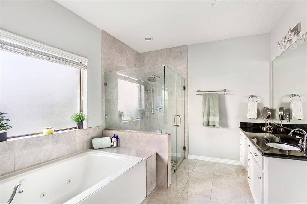 The primary retreat boasts a bright bathroom with dual sinks, a bathtub-shower combo, and ample natural light.