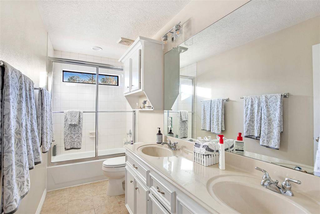 Luxury in simplicity – a bright bathroom with dual sinks, a glass shower door, and timeless design.