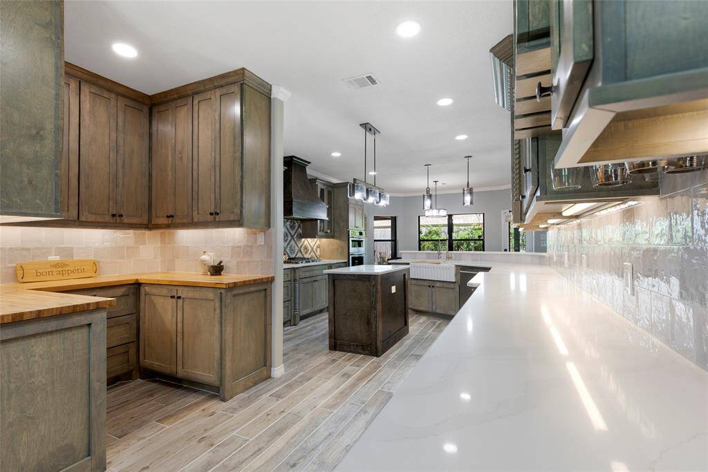 This elegant kitchen offers a large island with generous storage, a built-in wine fridge, and a butler pantry, creating a perfect space for entertaining and culinary arts. The sophisticated pendant lighting and high-end appliances appeal to buyers looking for luxury.