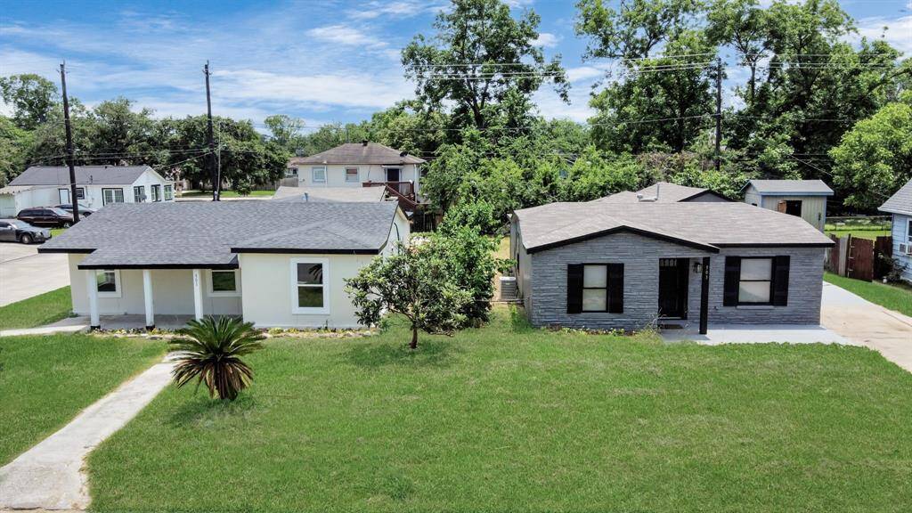 This photo showcases two charming single-story homes with well-maintained lawns. Both houses have modern exteriors, one in white and the other in gray, and are surrounded by lush greenery, providing a welcoming neighborhood feel.