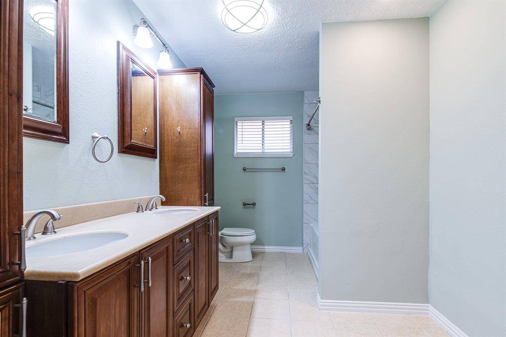This secondary bathroom features double sinks for added convenience, a showing-bath combo, and brand-new tile and fixtures. Perfect for busy mornings or relaxing evenings!